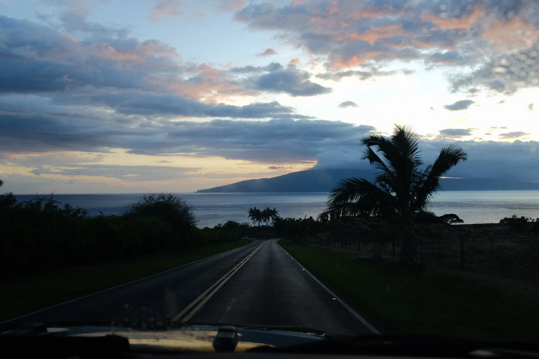 Coast road at dusk with an island silhouetted across the channel