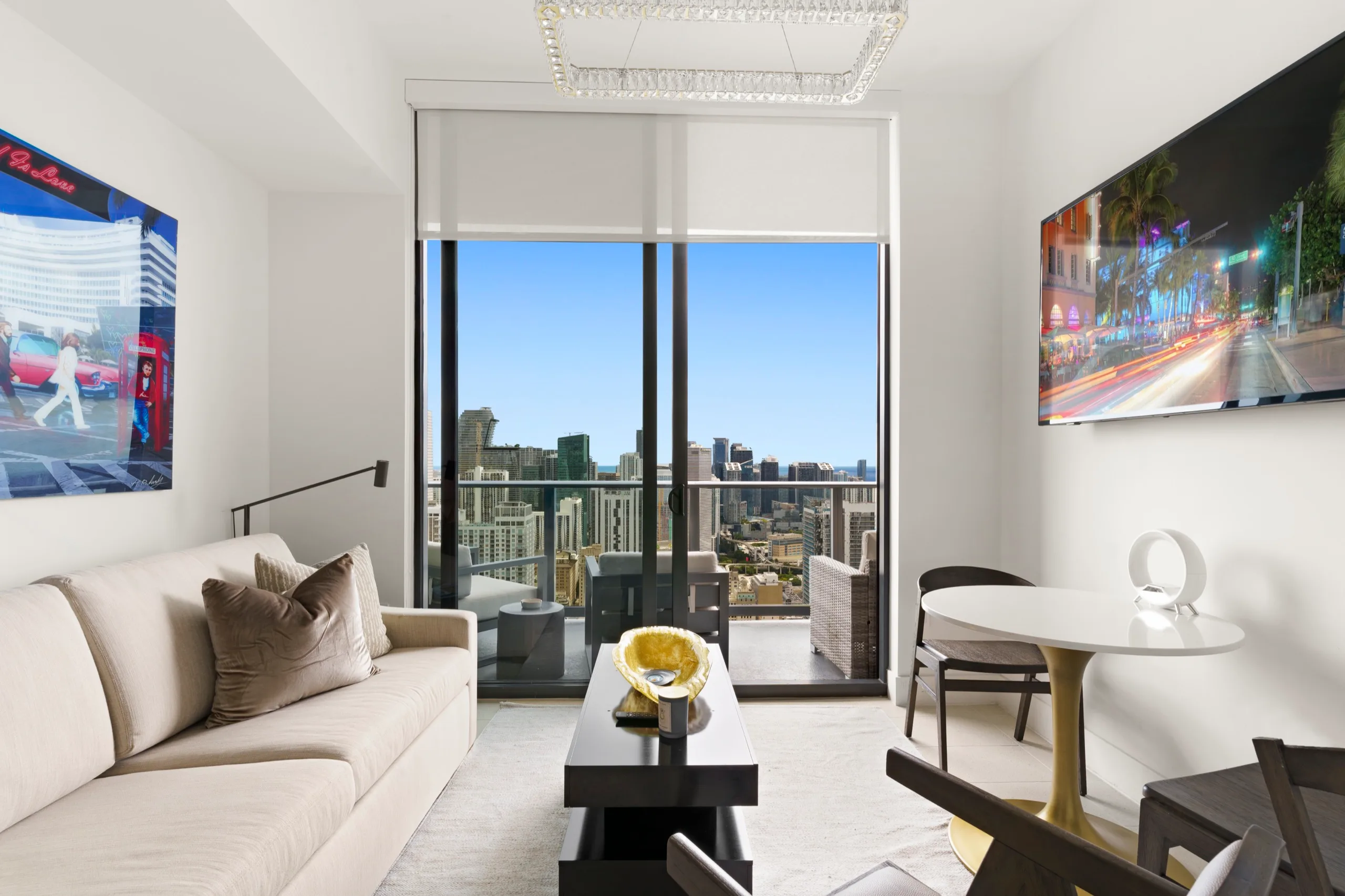 High-rise living room with floor-to-ceiling glass over the Miami skyline, cream sofa and pale marble table