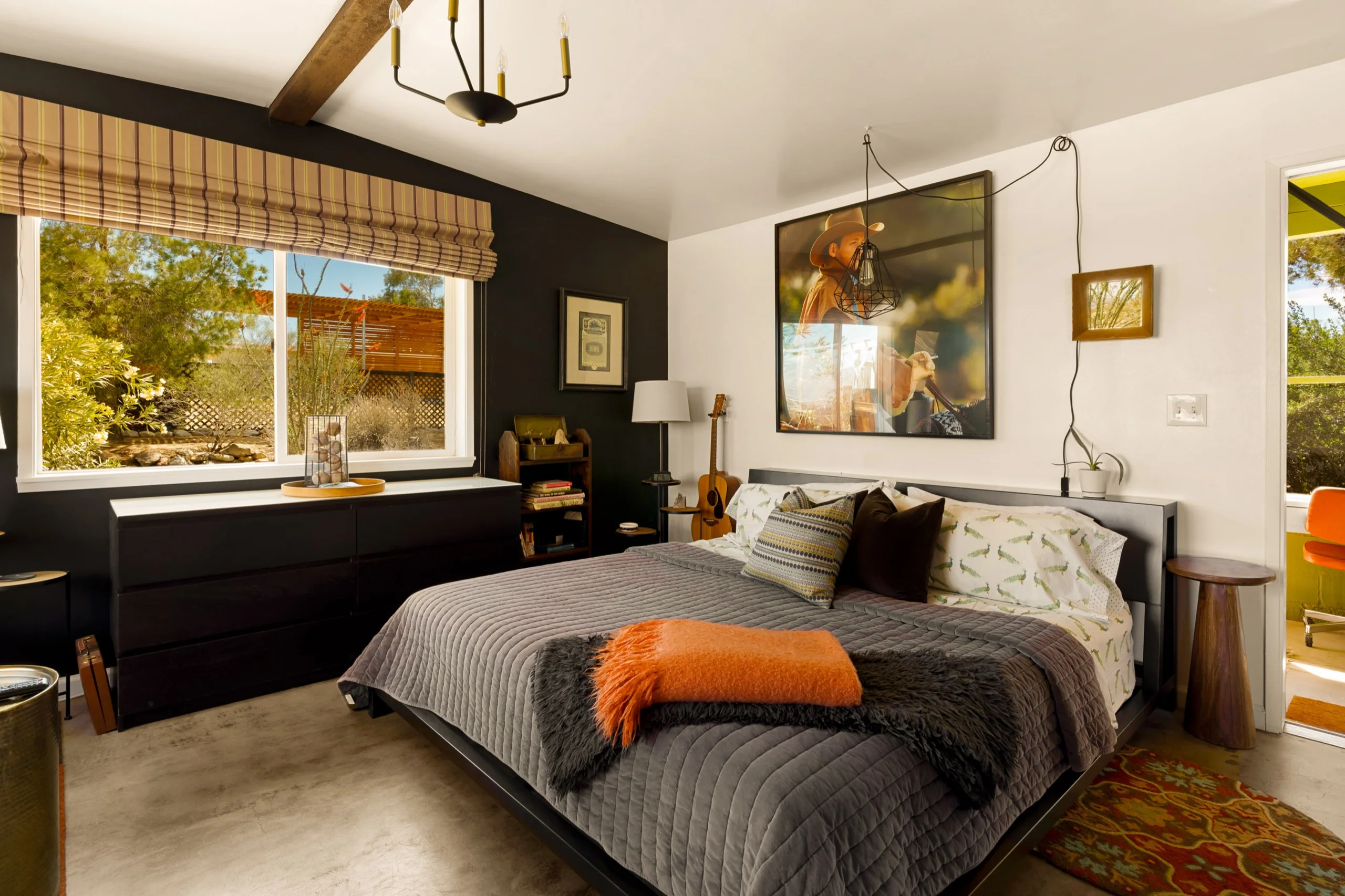 Bedroom with charcoal feature wall, exposed beam and a burnt-orange throw across the bed