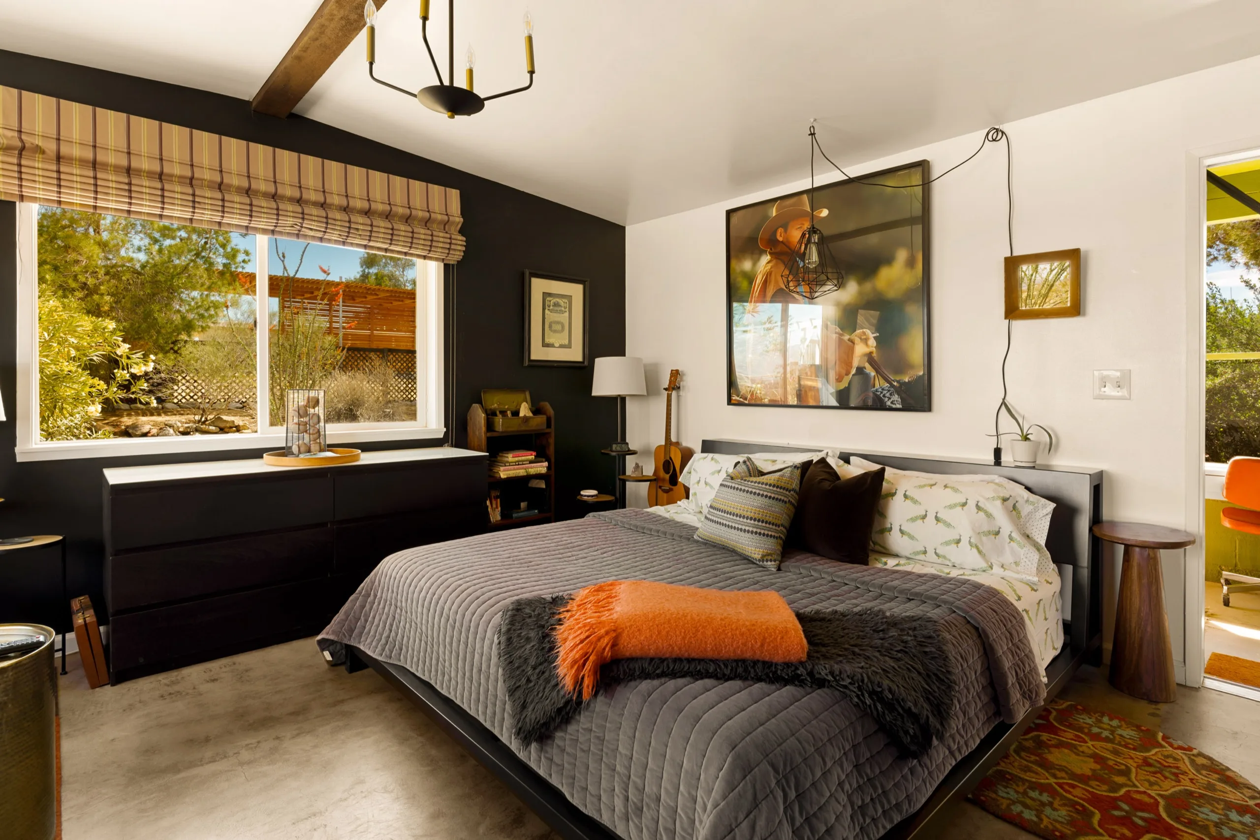 Bedroom with charcoal feature wall, exposed beam and a burnt-orange throw across the bed