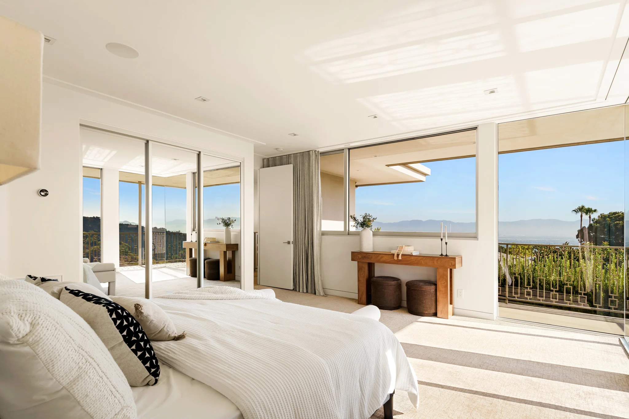 Bed made in white linen, a sliding partition open to the vanity and the terrace beyond