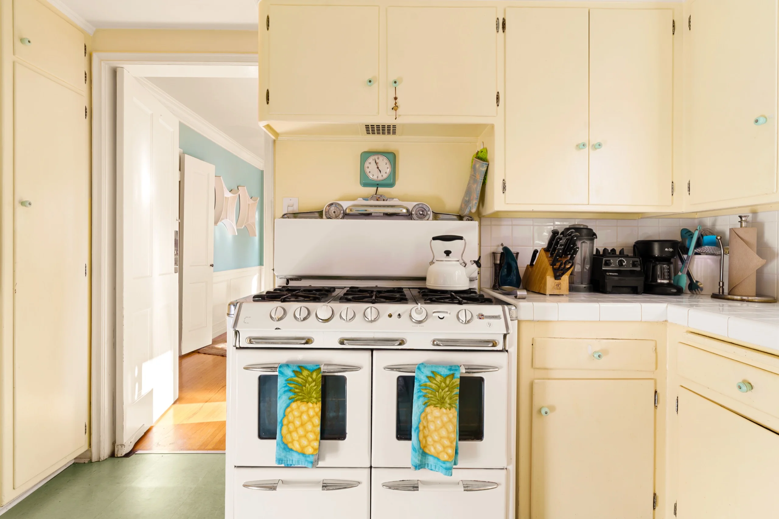 Original cream kitchen with a vintage gas range, tiled counters and a doorway through to the hall