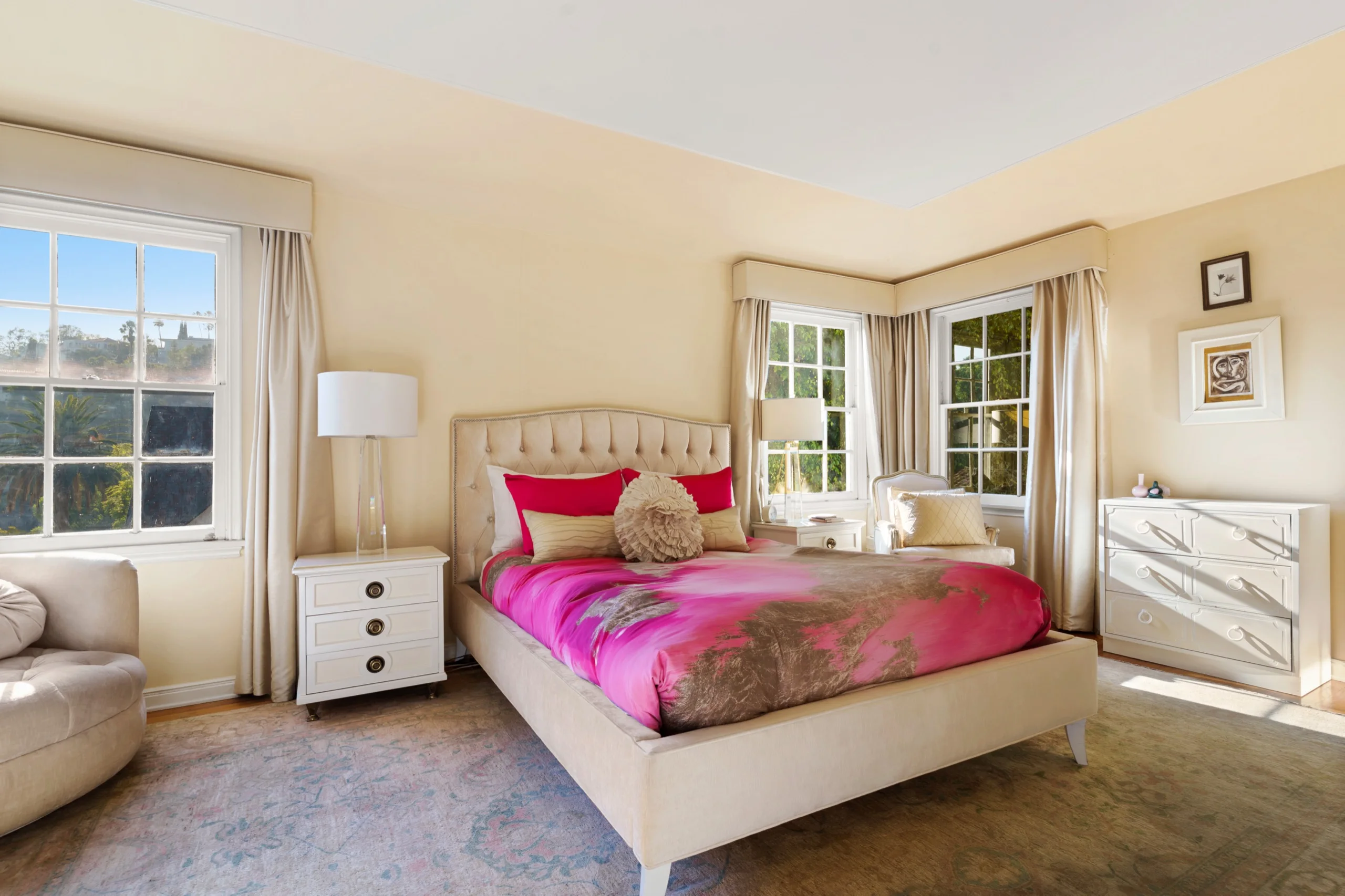 Bedroom with a buttoned headboard and magenta bedding, windows on two sides onto the canyon