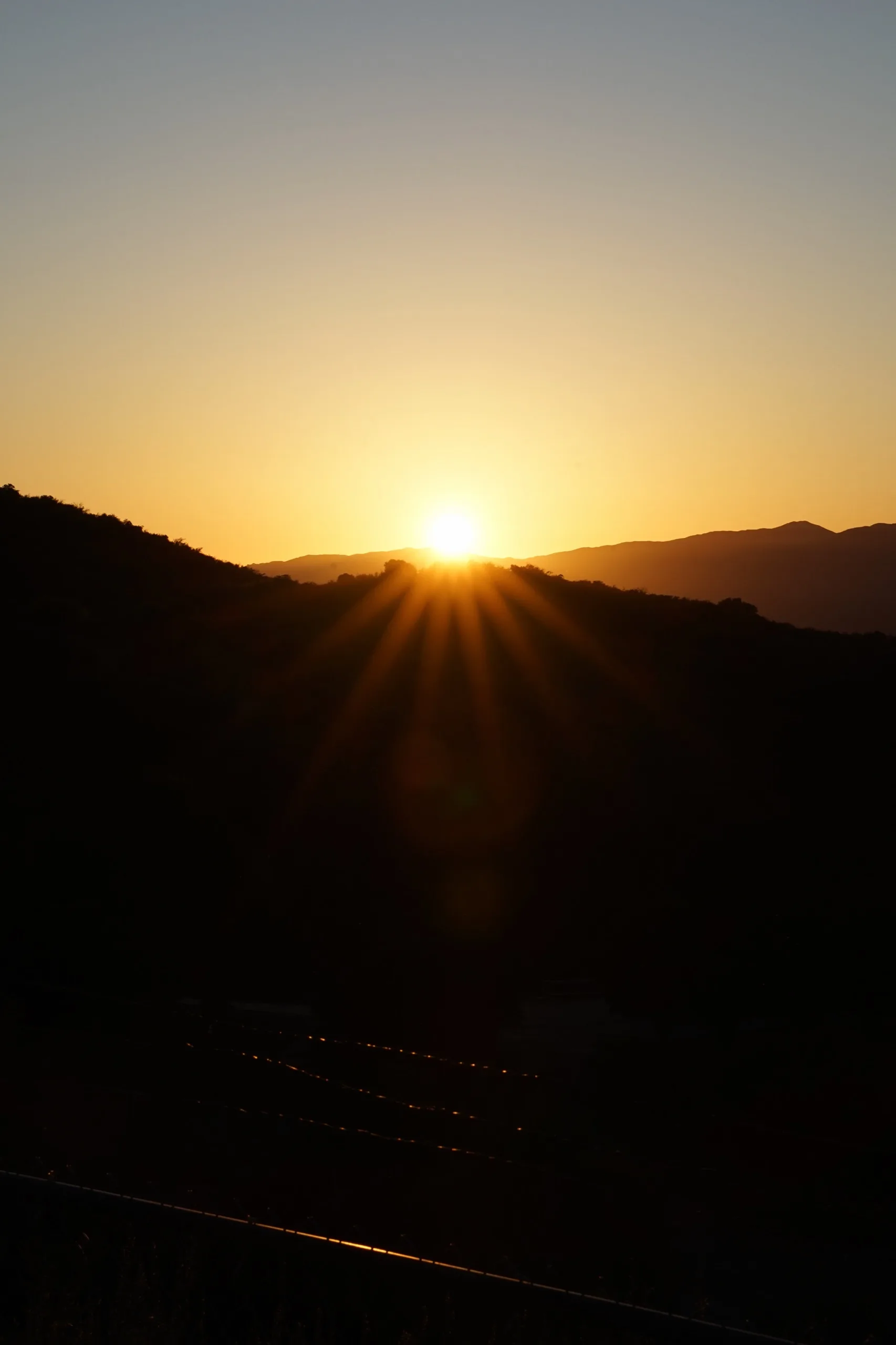 Sun bursting over a dark mountain ridge at first light