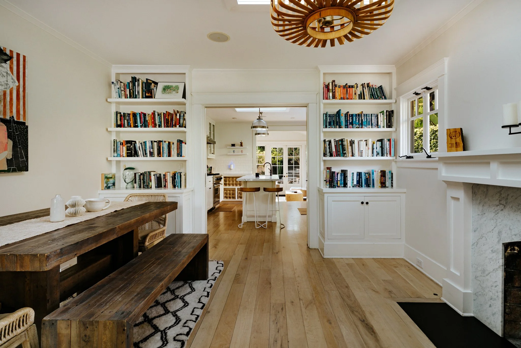 Built-in bookshelves either side of an opening through to the kitchen, a reclaimed timber bench along the wall