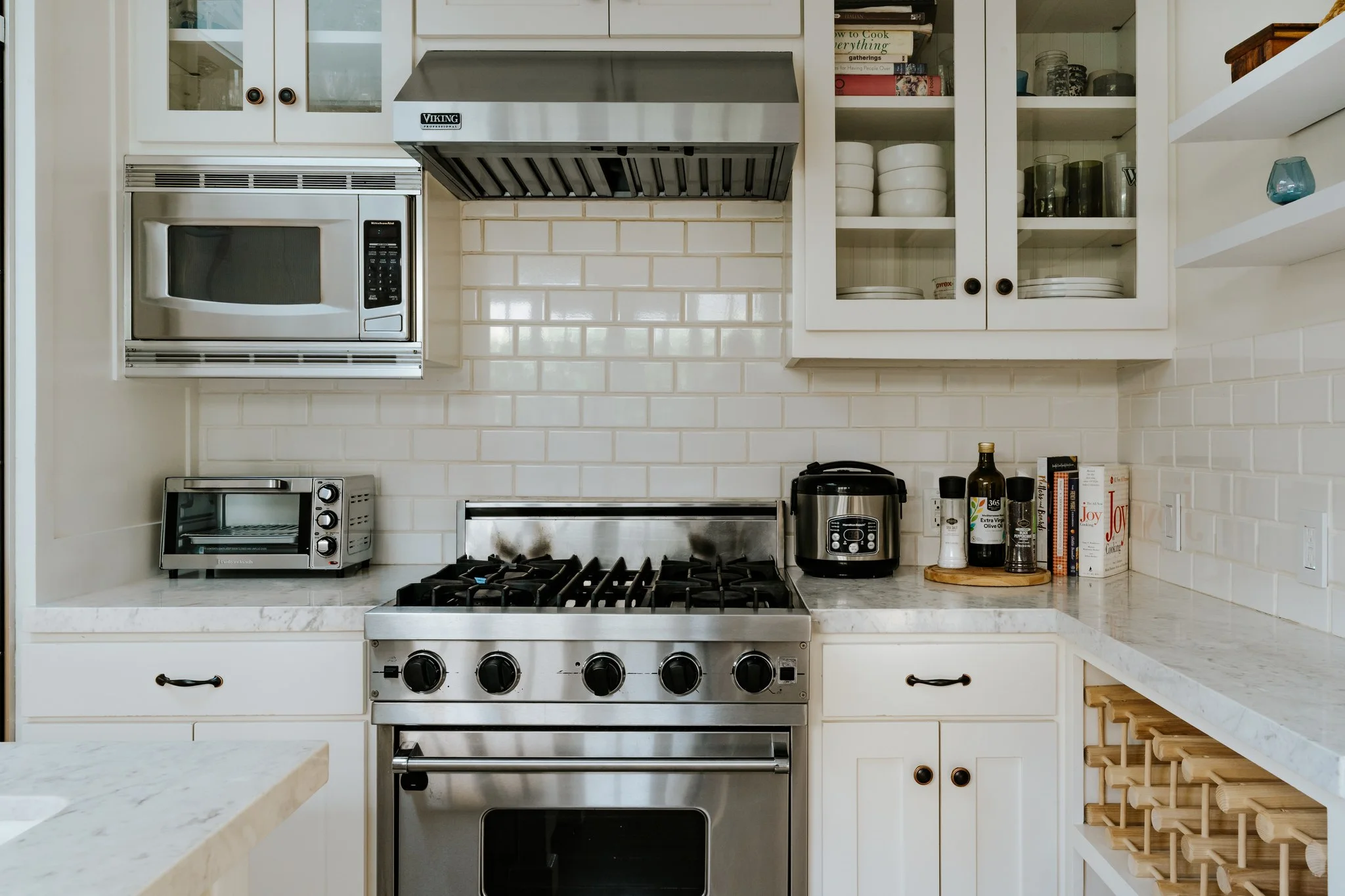 Range and subway-tiled splashback in the kitchen, glazed cabinets and a marble counter alongside